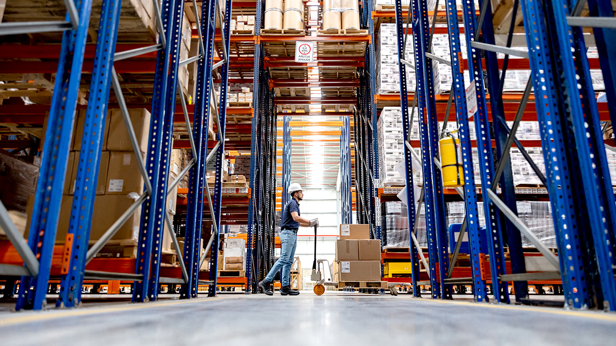 Man working at a distribution warehouse and moving boxes using a forklift